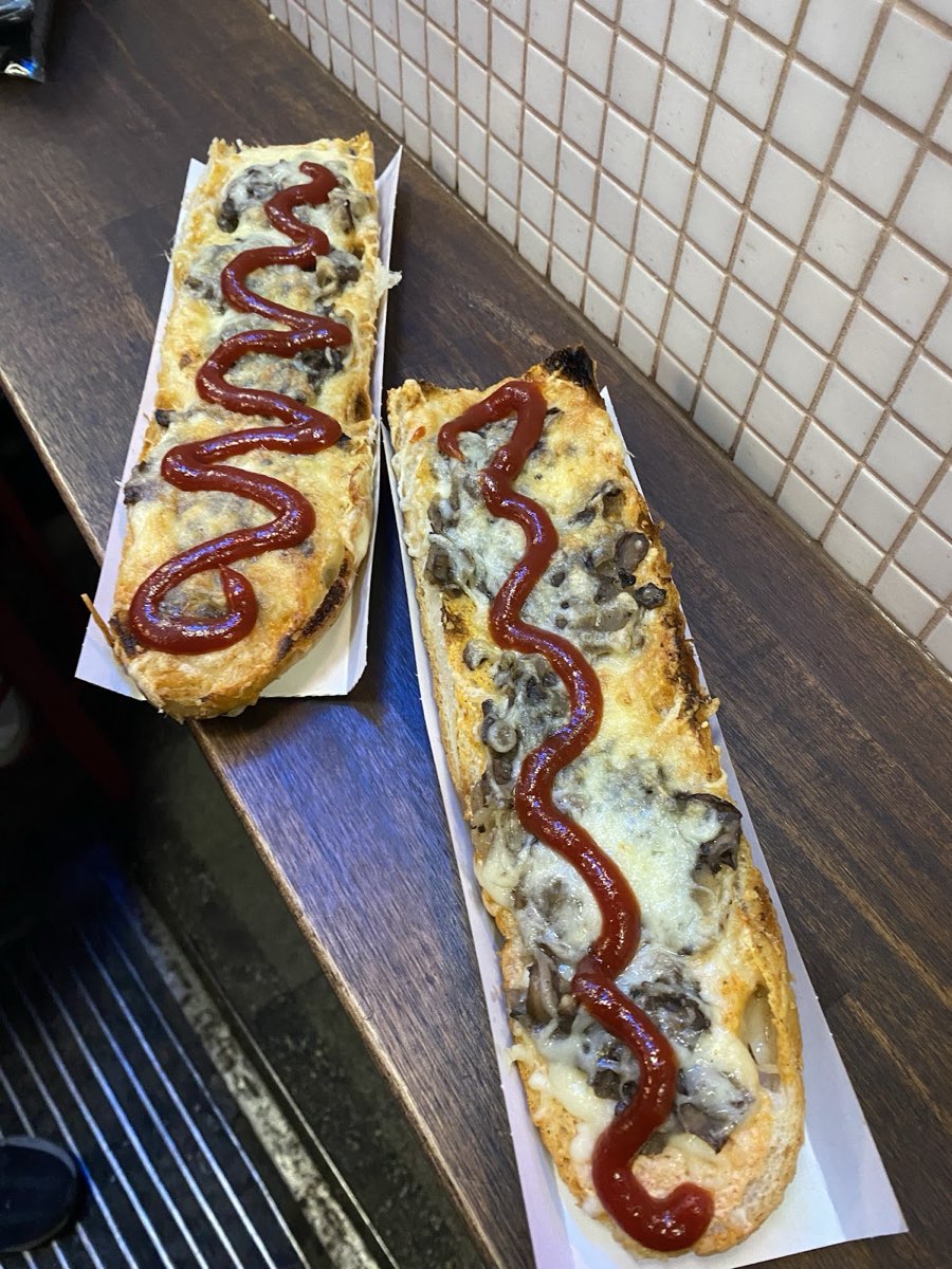 Zapiekanka ułożona na ukos z serem, pieczarkami i zygzakiem ketchupu